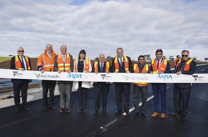 Collection of safety vest people behind a banner ribbon to celebrate the Sneydes Road opening