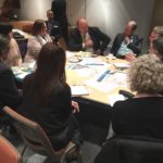 Nine people sitting around a table with engagement material on the table in discussion for La Trobe