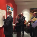 Five people review engagement brochures for La Trobe