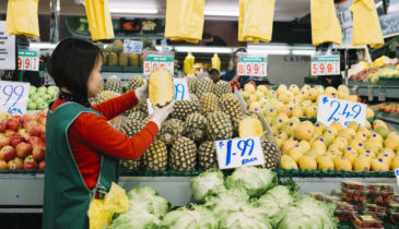Image of the Preston Market fruit and vegetable seller in front of food stalls
