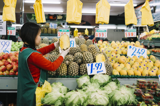 Image of the Preston Market fruit and vegetable seller in front of food stalls